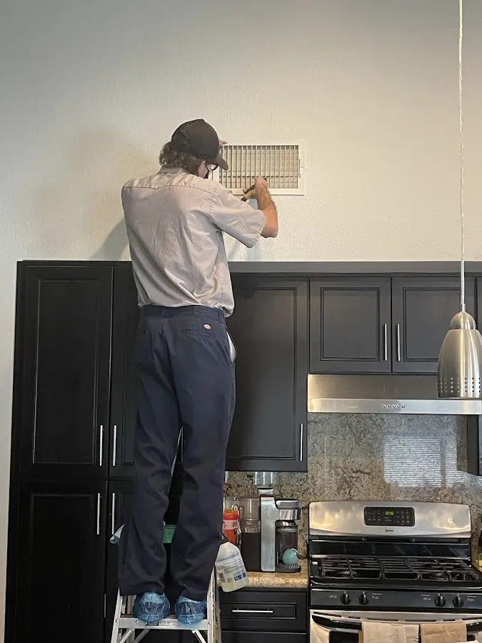Technician inspecting an air vent during HVAC service in Naples